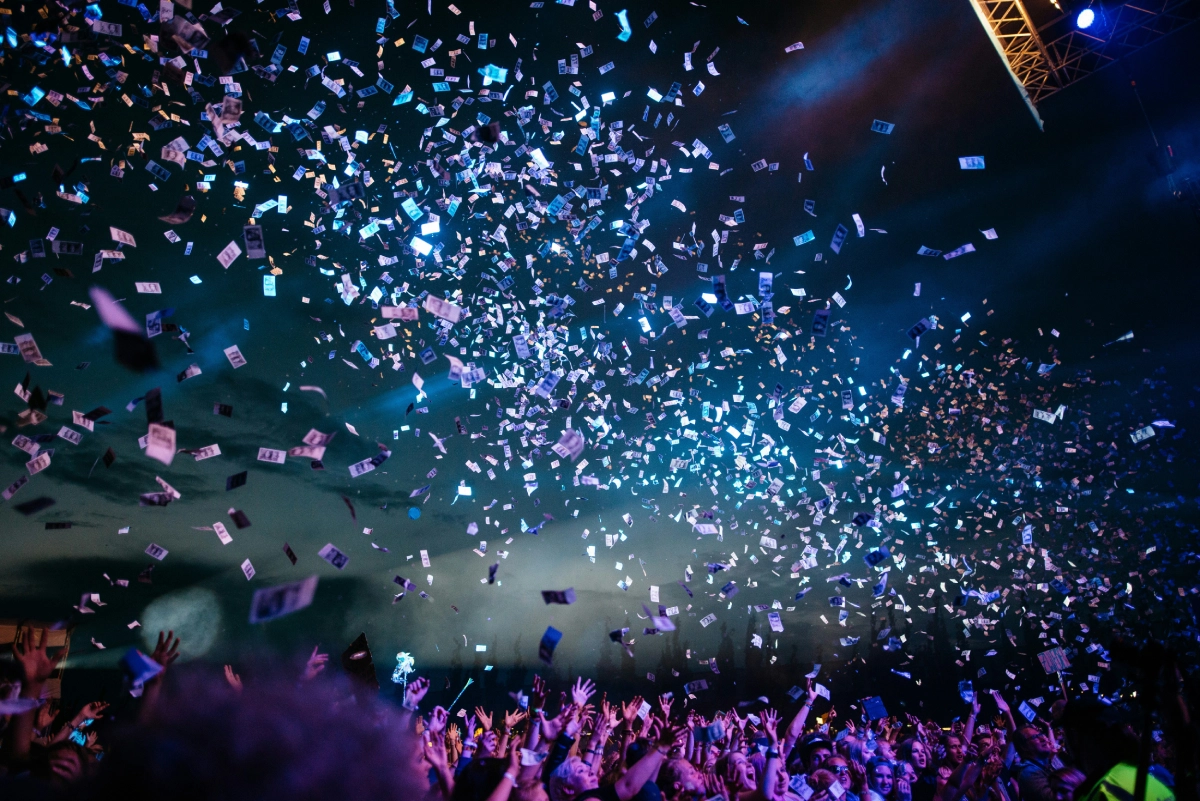 Colorful confetti rains down on a crowd at a lively event.