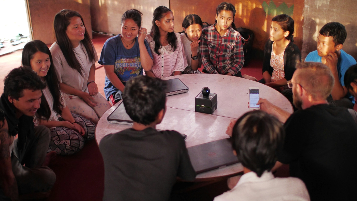 A group of young people sitting around a round table in a warm-lit room.