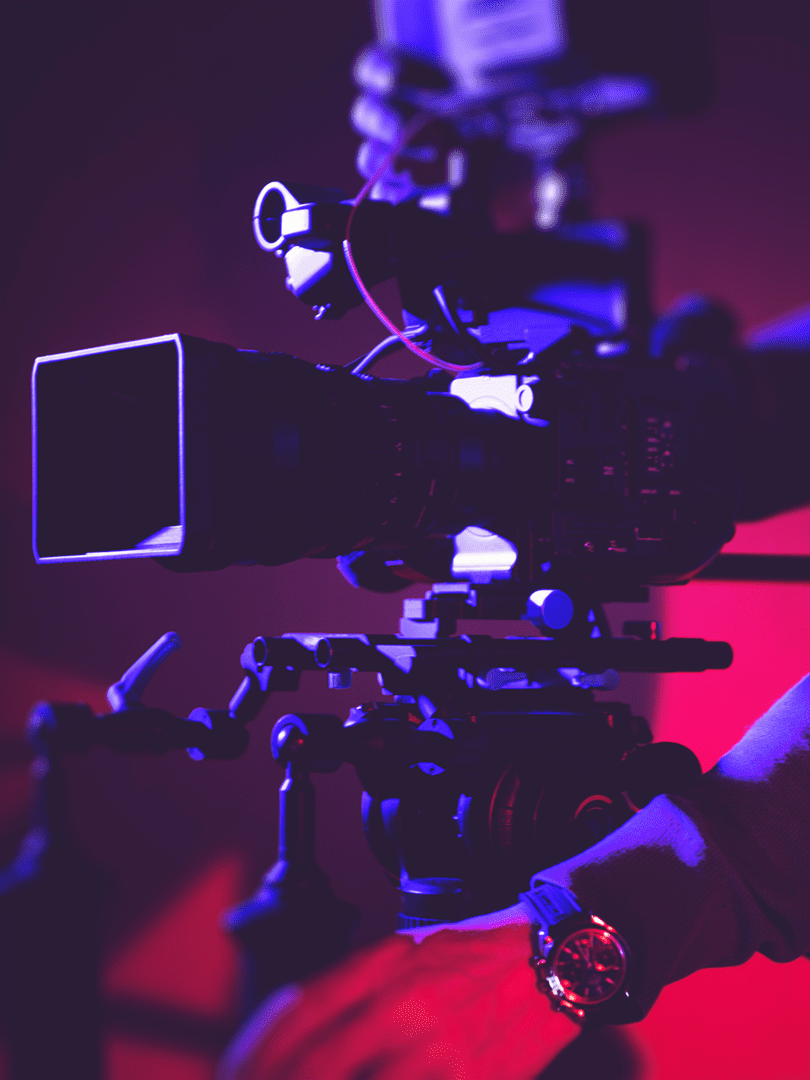 A professional video camera setup with purple and red lighting.