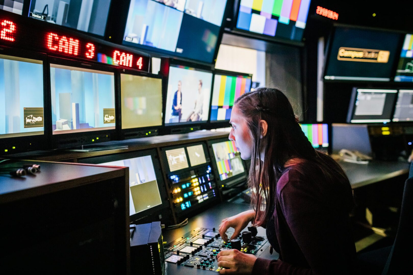 A woman operating video production equipment in a control room.